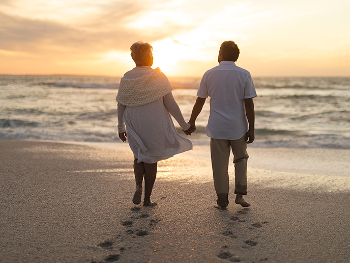 seniors holding hands on the beach at sunset reasonable rate of return in retirement
