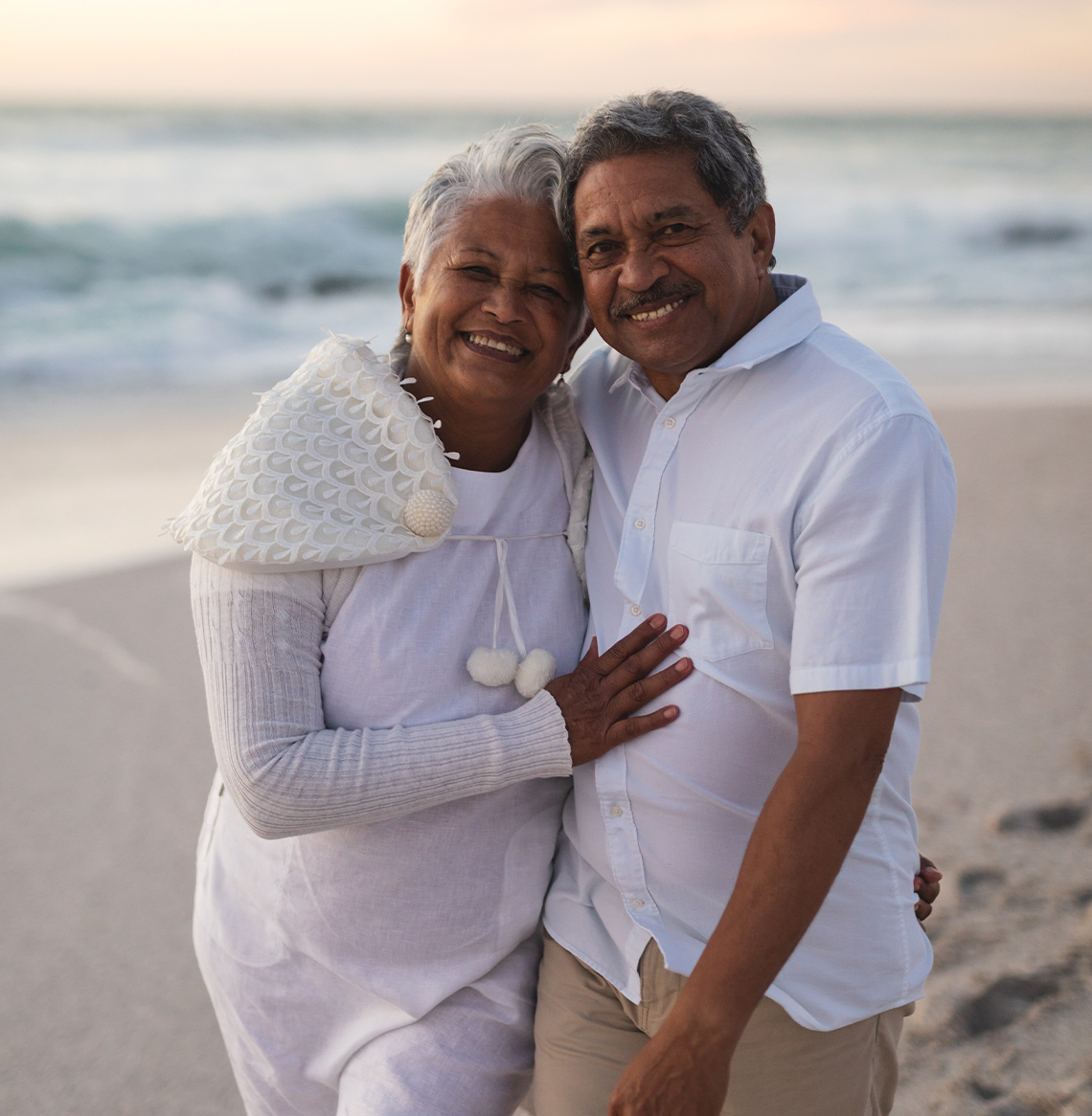 smiling senior couple on beach dressed in white annuity income freedom dream team california